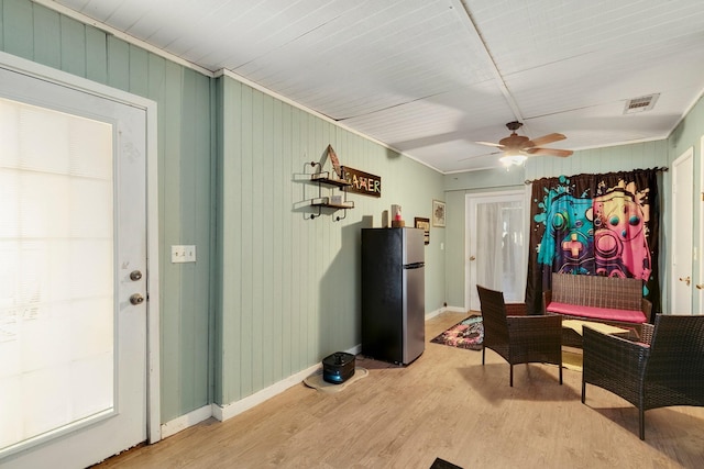 living area with ceiling fan, light wood-style floors, visible vents, and baseboards