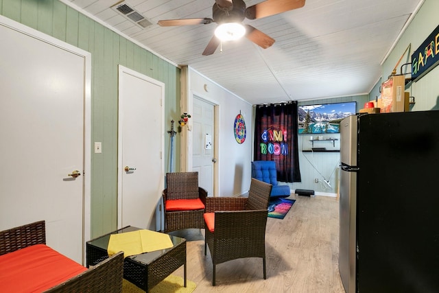 living area with visible vents, ornamental molding, and light wood finished floors