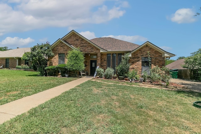 ranch-style home featuring brick siding, a front lawn, and roof with shingles