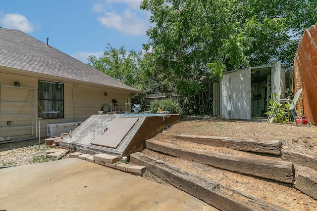 entry to storm shelter with an outbuilding, a storage shed, and fence