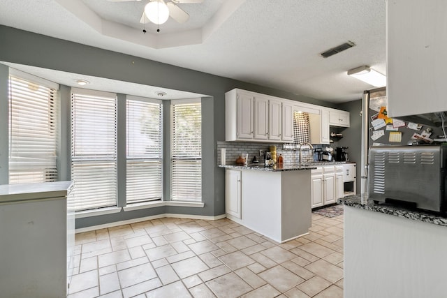 kitchen with visible vents, white cabinetry, decorative backsplash, dark stone countertops, and a textured ceiling