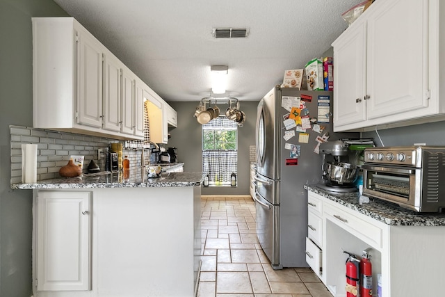 kitchen featuring a toaster, visible vents, white cabinets, and freestanding refrigerator