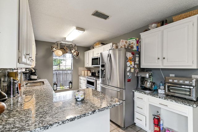 kitchen with visible vents, a toaster, stainless steel appliances, white cabinetry, and a sink