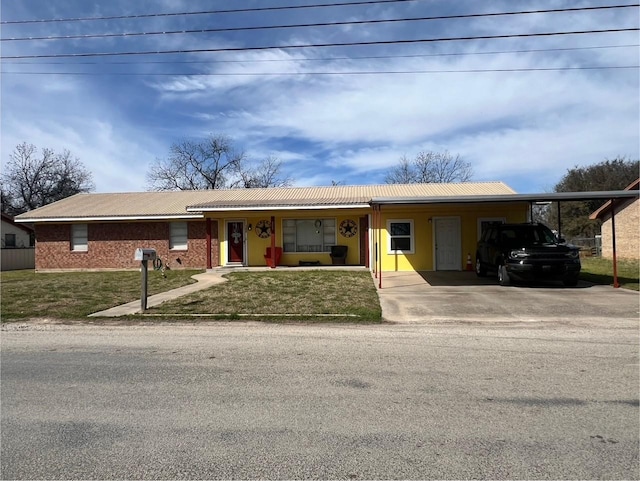 single story home with metal roof, driveway, an attached carport, and a front lawn