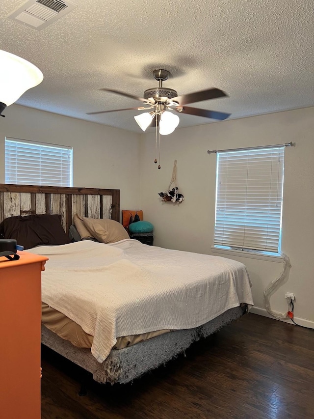 bedroom featuring a textured ceiling, wood finished floors, visible vents, and ceiling fan