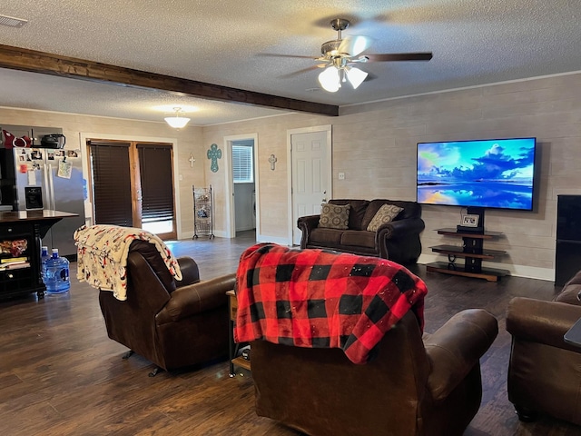 living area featuring visible vents, beamed ceiling, wood finished floors, a textured ceiling, and a ceiling fan