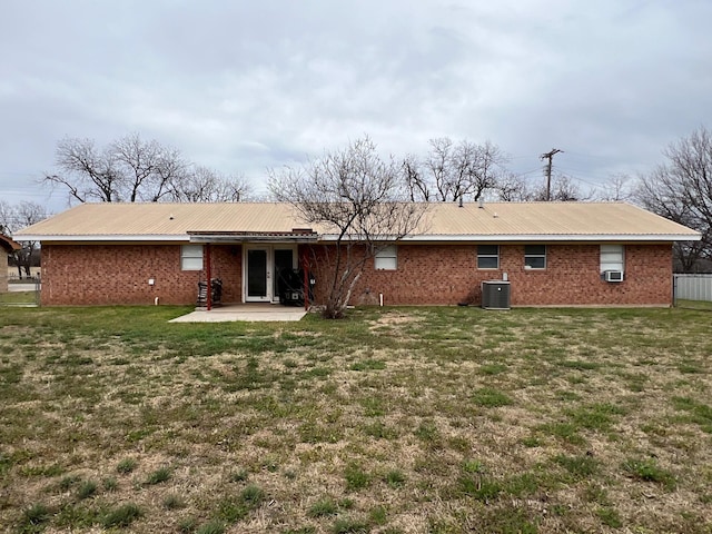 back of property with a yard, brick siding, central AC, and a patio area