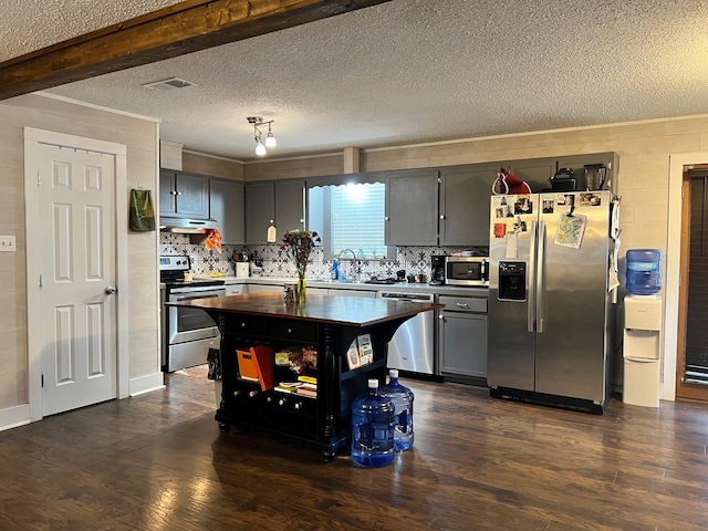 kitchen featuring dark wood finished floors, decorative backsplash, appliances with stainless steel finishes, and under cabinet range hood