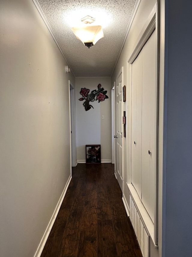 hallway with baseboards, a textured ceiling, and wood finished floors