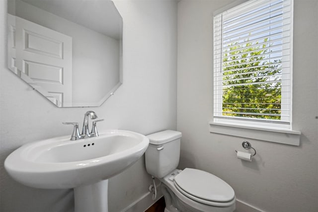 bathroom with a sink, baseboards, and toilet