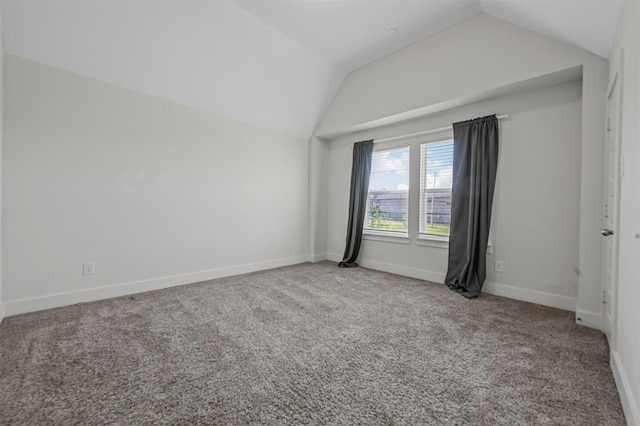 spare room featuring vaulted ceiling, carpet, and baseboards