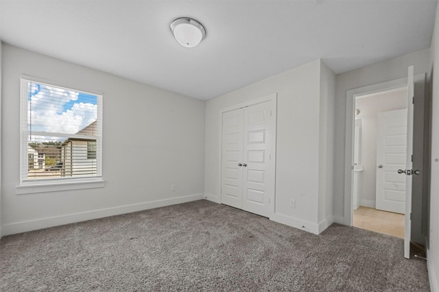 unfurnished bedroom with carpet flooring, baseboards, and a closet