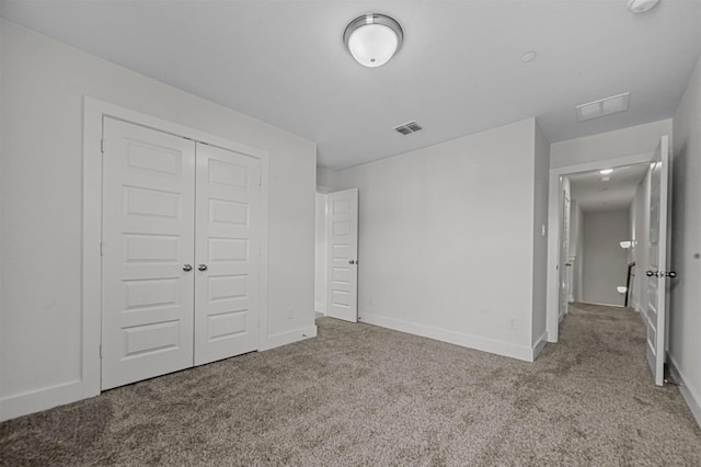 unfurnished bedroom with a closet, visible vents, baseboards, and carpet