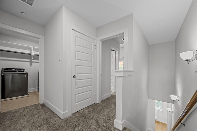 hallway with baseboards, carpet, and washer / dryer