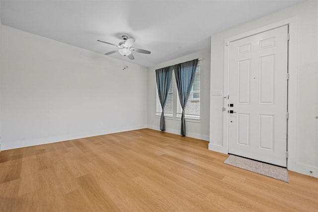 empty room with baseboards, a ceiling fan, and light wood finished floors