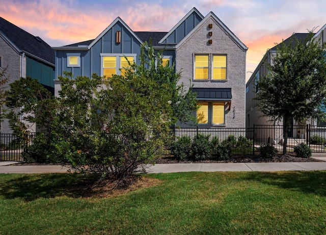 view of front of home featuring a fenced front yard, board and batten siding, brick siding, and a front lawn