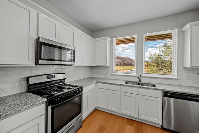 kitchen with a sink, white cabinetry, light wood finished floors, and stainless steel appliances