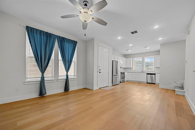 unfurnished living room featuring baseboards, visible vents, and light wood finished floors