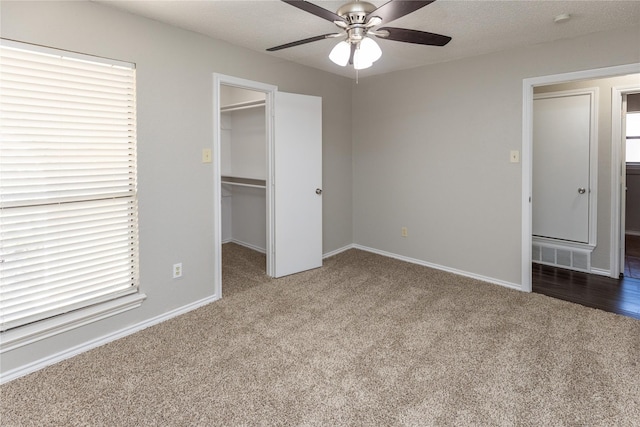 unfurnished bedroom featuring visible vents, baseboards, a walk in closet, and carpet