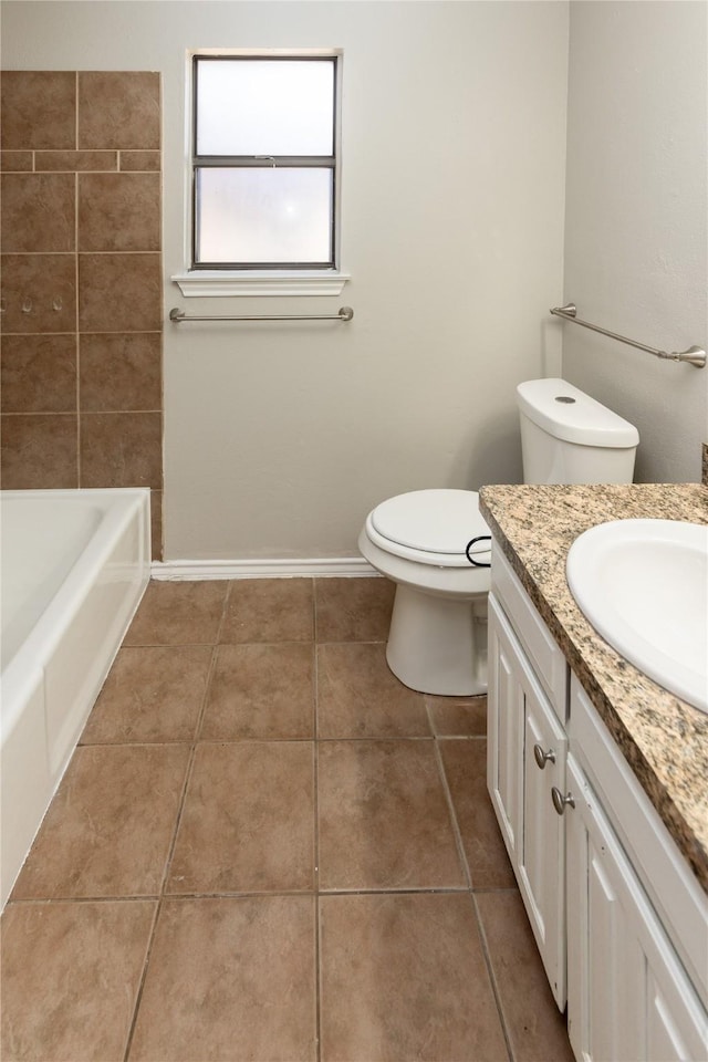 bathroom featuring vanity, a bath, baseboards, tile patterned flooring, and toilet