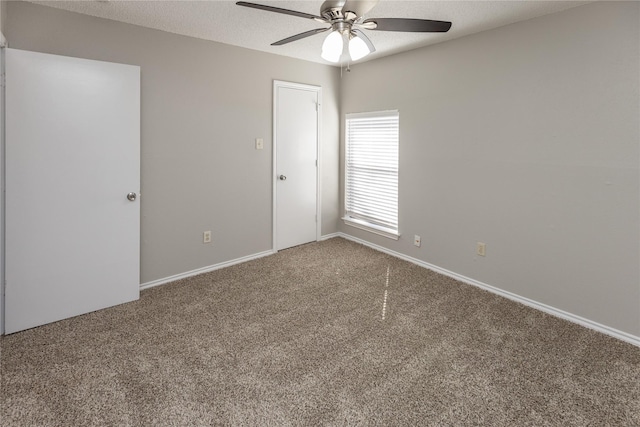 carpeted spare room featuring baseboards, a textured ceiling, and a ceiling fan