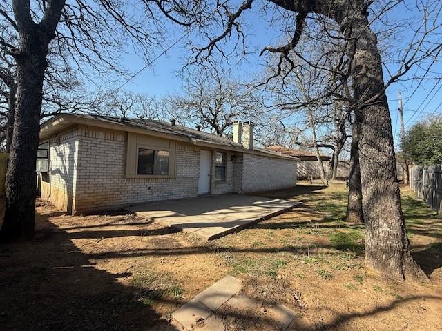 back of house with fence, brick siding, and a chimney