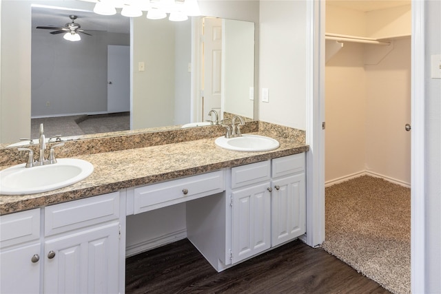 bathroom featuring a sink, a walk in closet, double vanity, and a ceiling fan