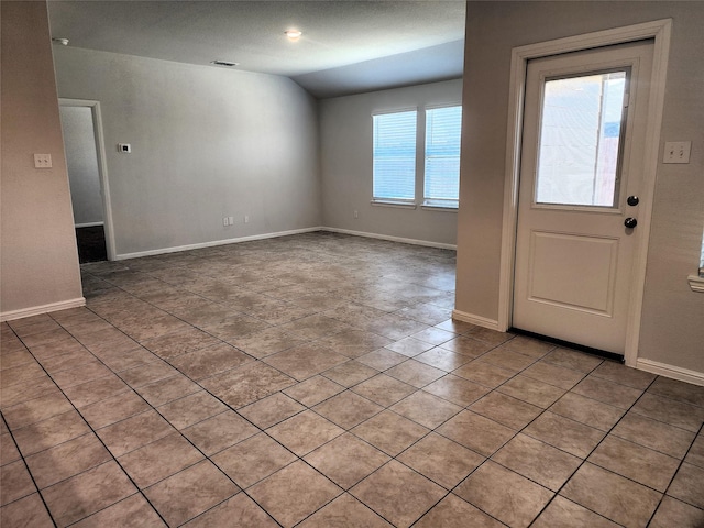 foyer with vaulted ceiling, light tile patterned flooring, baseboards, and visible vents