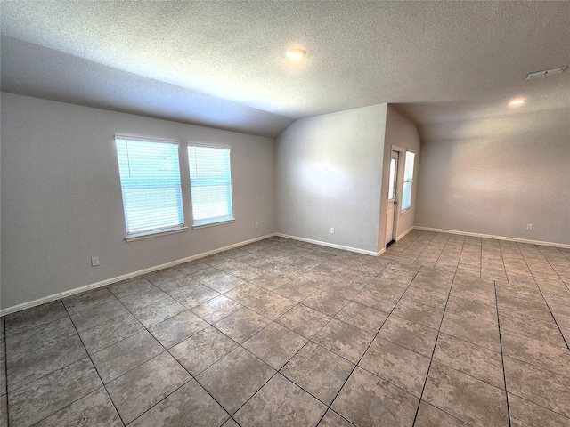 spare room featuring tile patterned floors, visible vents, baseboards, and vaulted ceiling