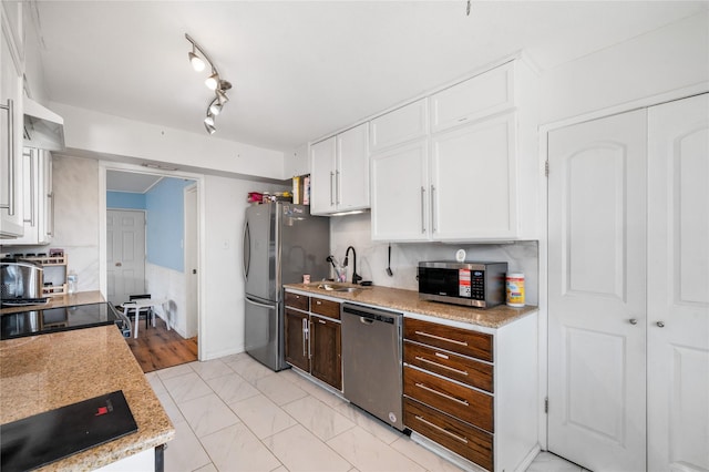 kitchen featuring a sink, stainless steel appliances, dark brown cabinetry, white cabinets, and light countertops