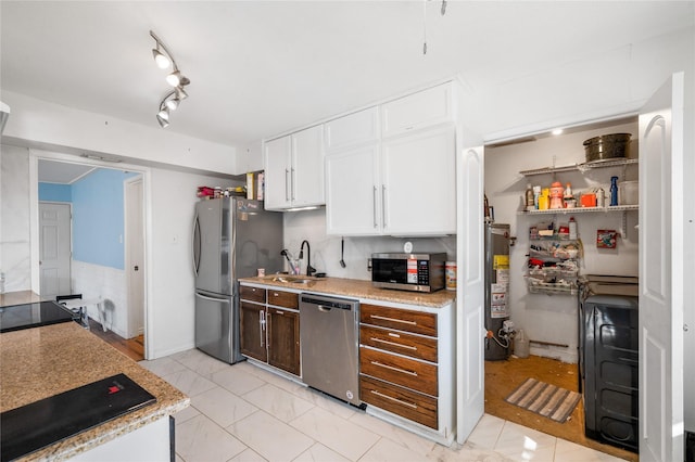 kitchen featuring water heater, rail lighting, stainless steel appliances, white cabinetry, and a sink