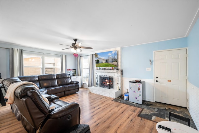 living area featuring a fireplace, ceiling fan, and wood finished floors