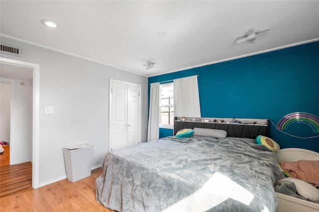 bedroom featuring a closet, visible vents, baseboards, and wood finished floors