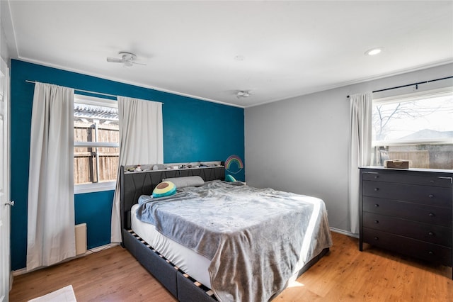 bedroom featuring baseboards, multiple windows, and wood finished floors