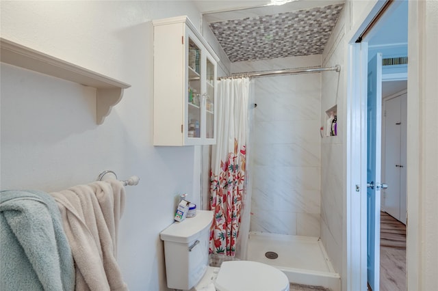 bathroom featuring a shower stall, toilet, and wood finished floors