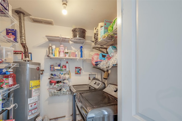 washroom with water heater, laundry area, visible vents, and separate washer and dryer