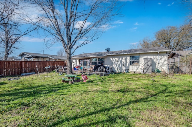 back of property featuring a yard and fence