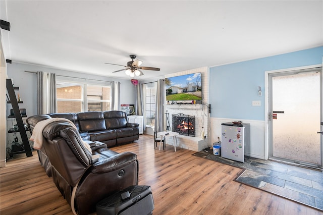 living area featuring a brick fireplace, wood finished floors, and ceiling fan