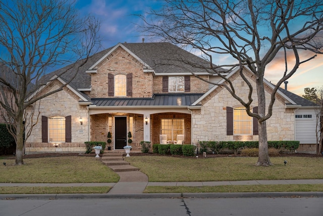 view of front of house with a lawn, a standing seam roof, roof with shingles, metal roof, and brick siding