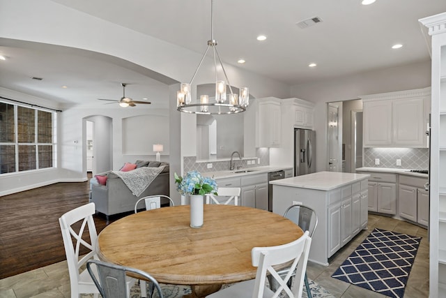 dining space with recessed lighting, visible vents, arched walkways, and ceiling fan with notable chandelier