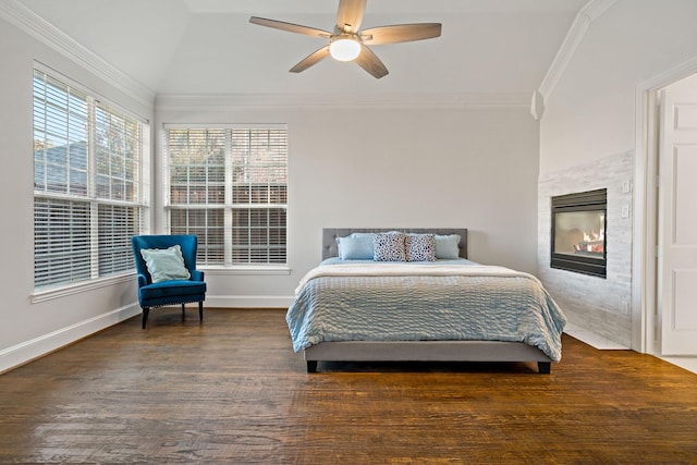 bedroom with a ceiling fan, wood finished floors, baseboards, ornamental molding, and a glass covered fireplace