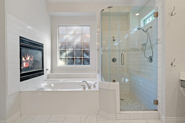 full bath featuring a bath, a glass covered fireplace, a stall shower, and baseboards