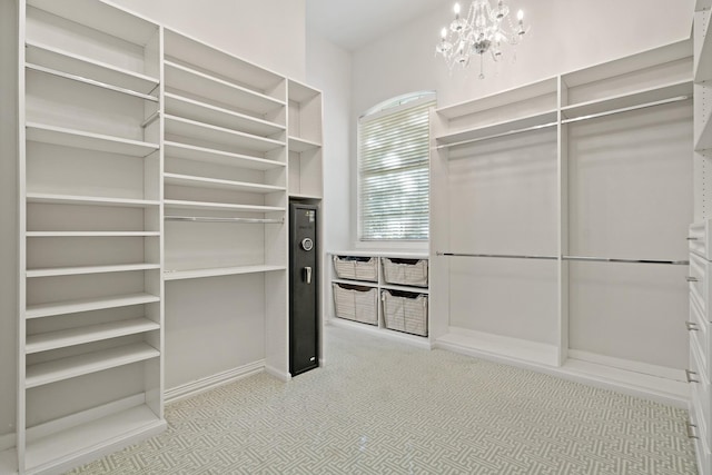 spacious closet with light colored carpet and a chandelier