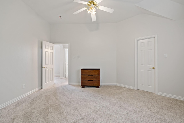 carpeted empty room featuring baseboards, a ceiling fan, and vaulted ceiling