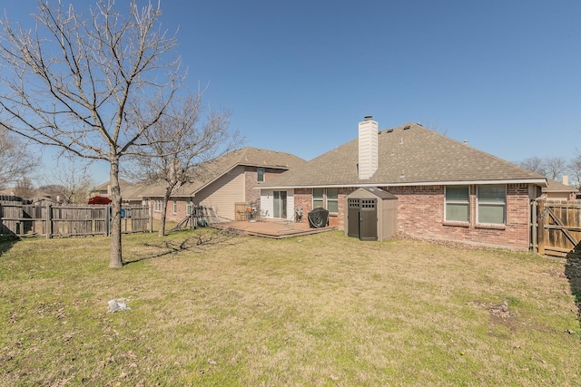 back of house with a gate, a fenced backyard, brick siding, and a yard