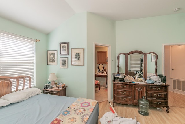 bedroom featuring visible vents, light wood-style floors, and lofted ceiling