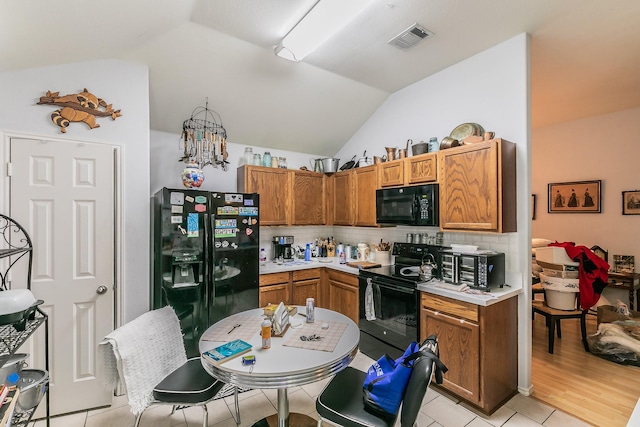 kitchen featuring visible vents, black appliances, tasteful backsplash, light countertops, and vaulted ceiling