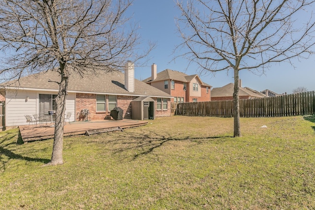 view of yard featuring a deck, an outbuilding, and a fenced backyard