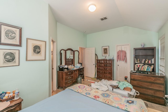 bedroom featuring visible vents, lofted ceiling, and wood finished floors