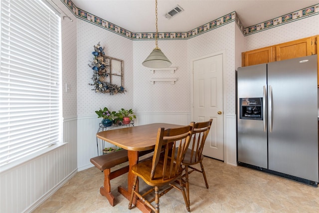 dining area with wallpapered walls, visible vents, and wainscoting